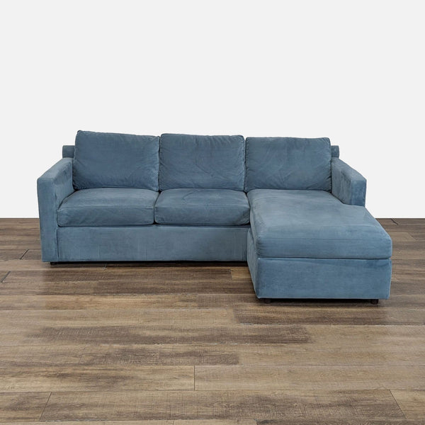 1. Blue Crate and Barrel sectional with track arms and a chaise with storage, shown on wood flooring.