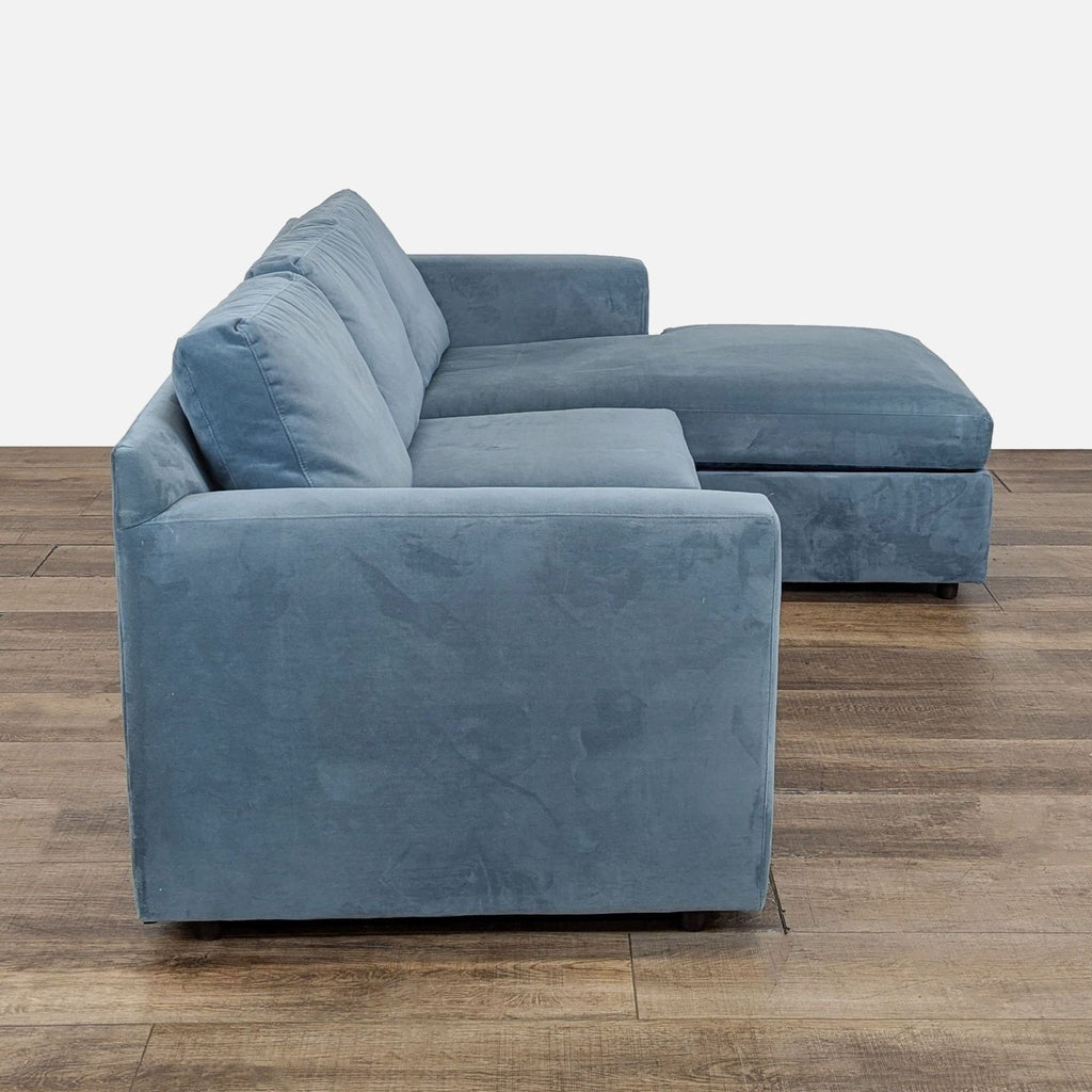 2. Side view of a Crate and Barrel blue sectional, displaying track arms and chaise lounge with storage.