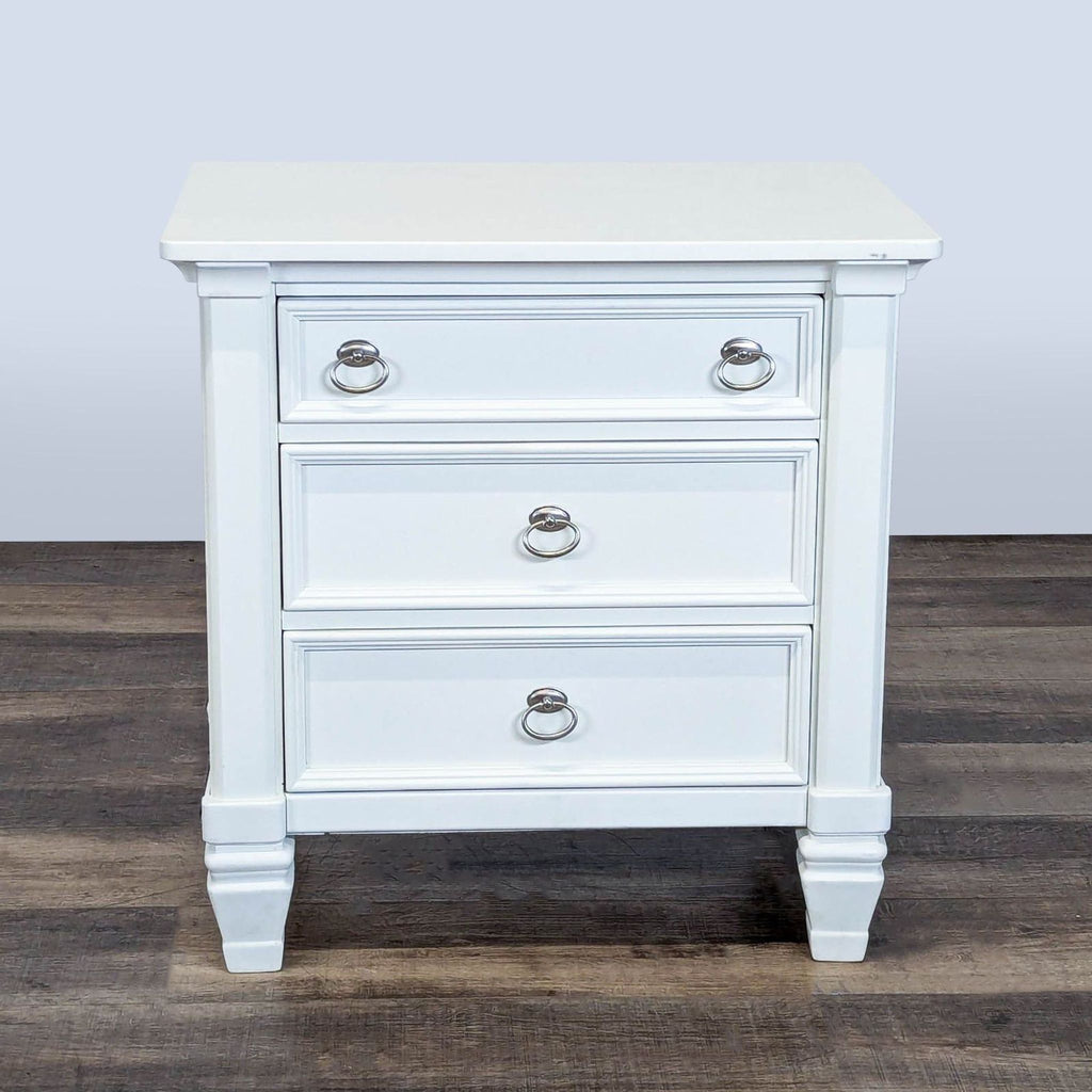 1. White Ashley Furniture end table with three dovetail drawers, metal ring pulls, and sturdy legs on wood flooring.