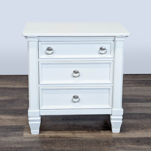 1. White Ashley Furniture end table with three dovetail drawers, metal ring pulls, and sturdy legs on wood flooring.