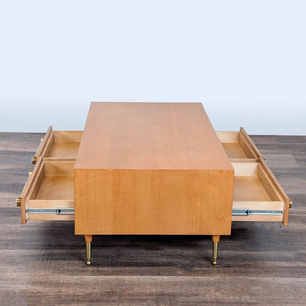 2. Side view of a wooden coffee table by Anthropologie with four drawers open on opposite sides.