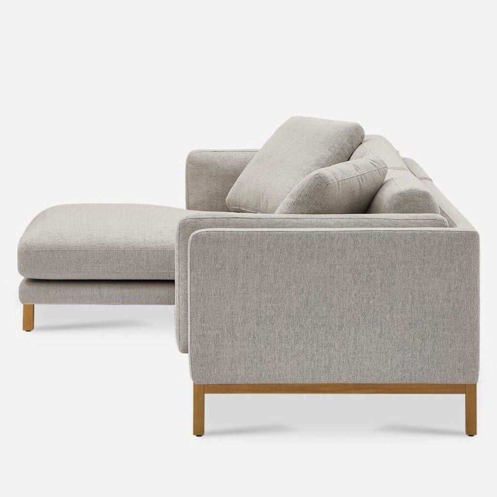 2. Side view of Castlery sectional, featuring soft cushions and a crisp, squared edge with wooden base.