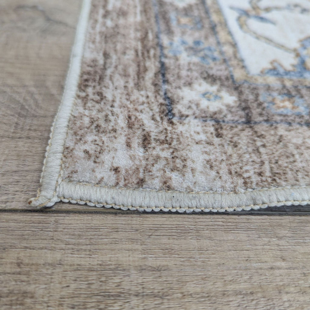 3. Detailed corner of the Reperch rug showing stitched edge and soft, patterned pile on a wooden surface.