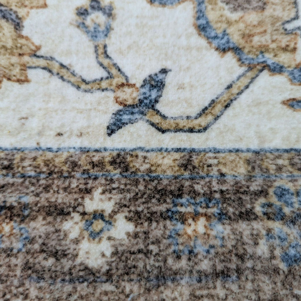 2. Close-up of Reperch rug’s pattern, featuring floral details and a small blue bird, in muted earth tones.