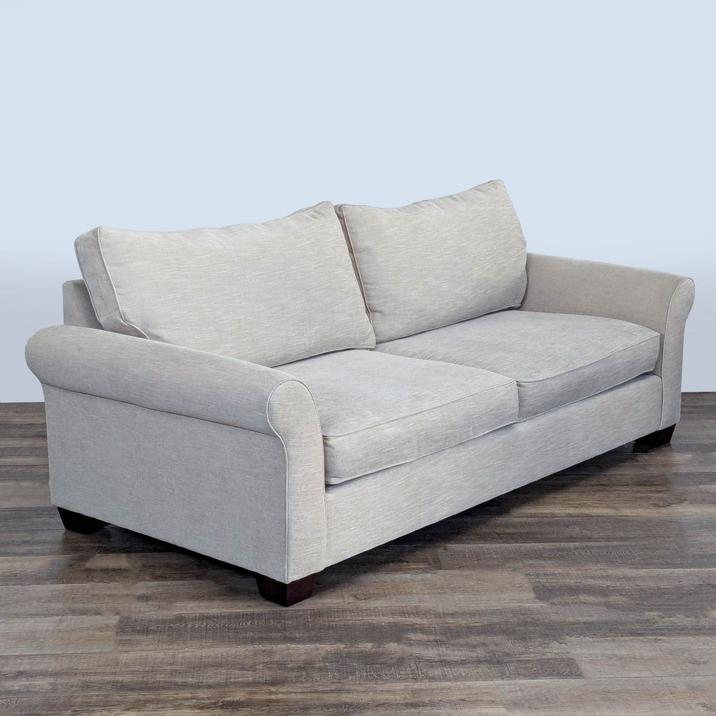 3. Angled view of Pottery Barn loveseat, highlighting rolled arms, loose cushions, and dark tapered legs.