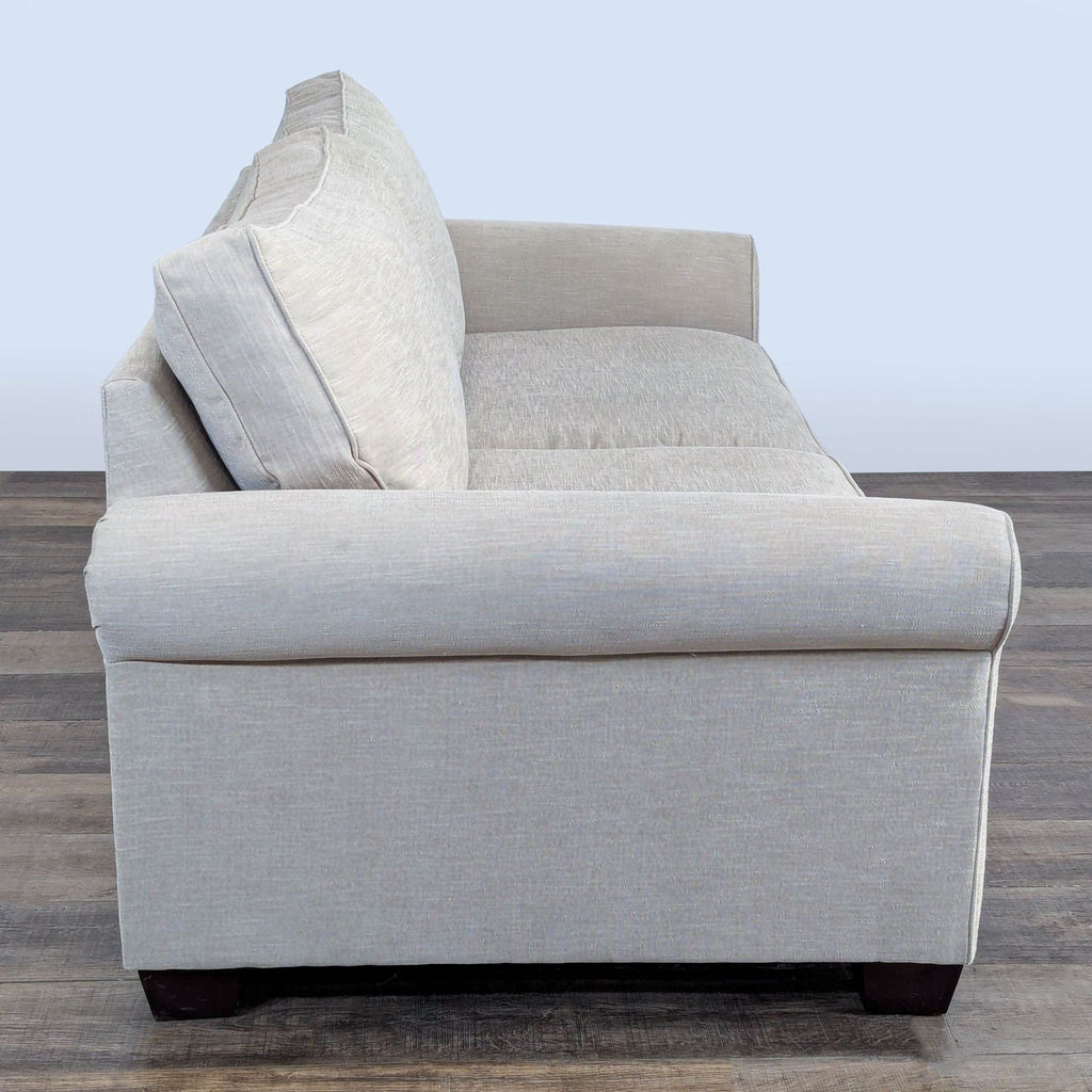 2. Side view of Pottery Barn loveseat, showing rolled armrests and loose cushions with espresso-finished legs.