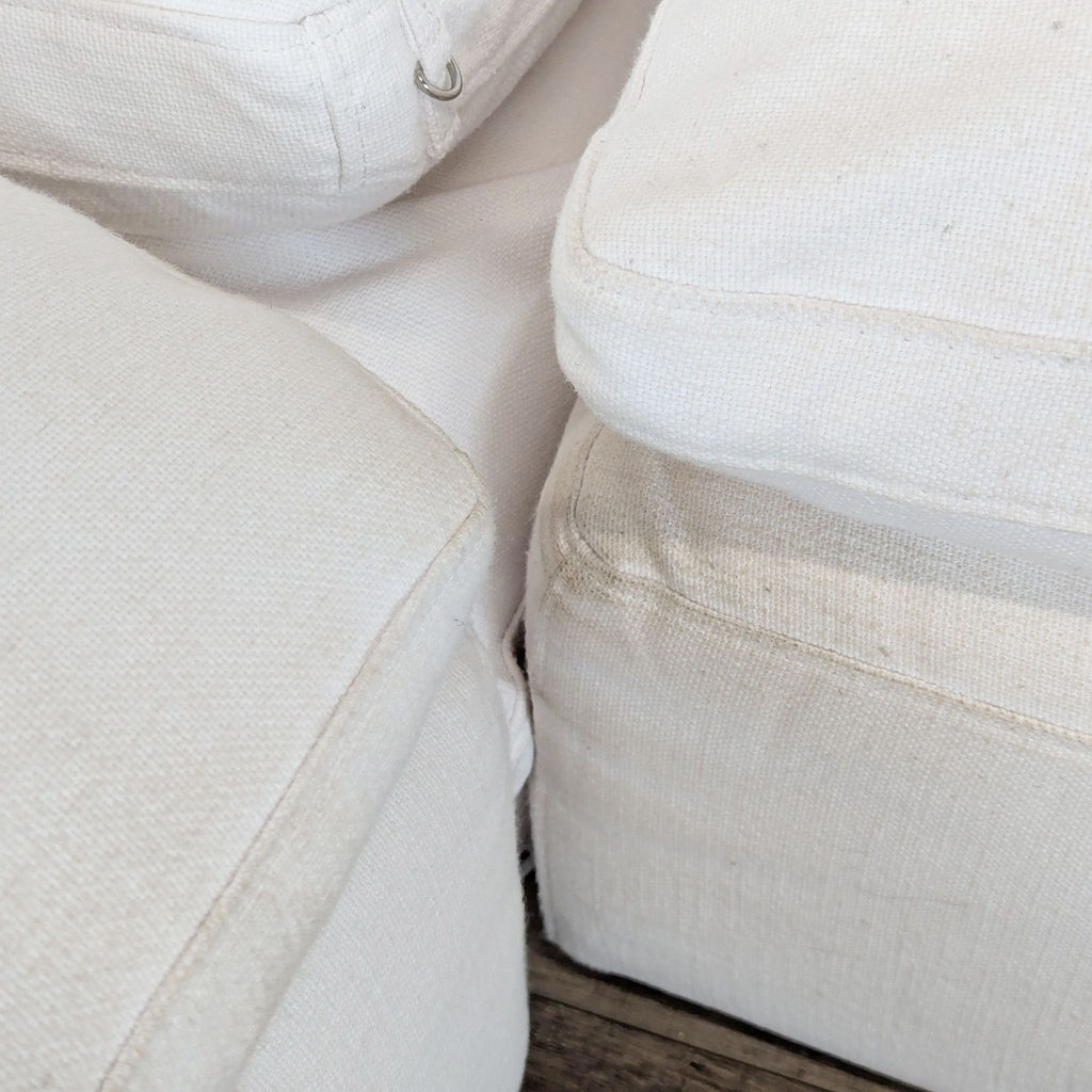 Close-up of the intersection between cushions on a white sectional, showing the textured fabric and stitching detail.