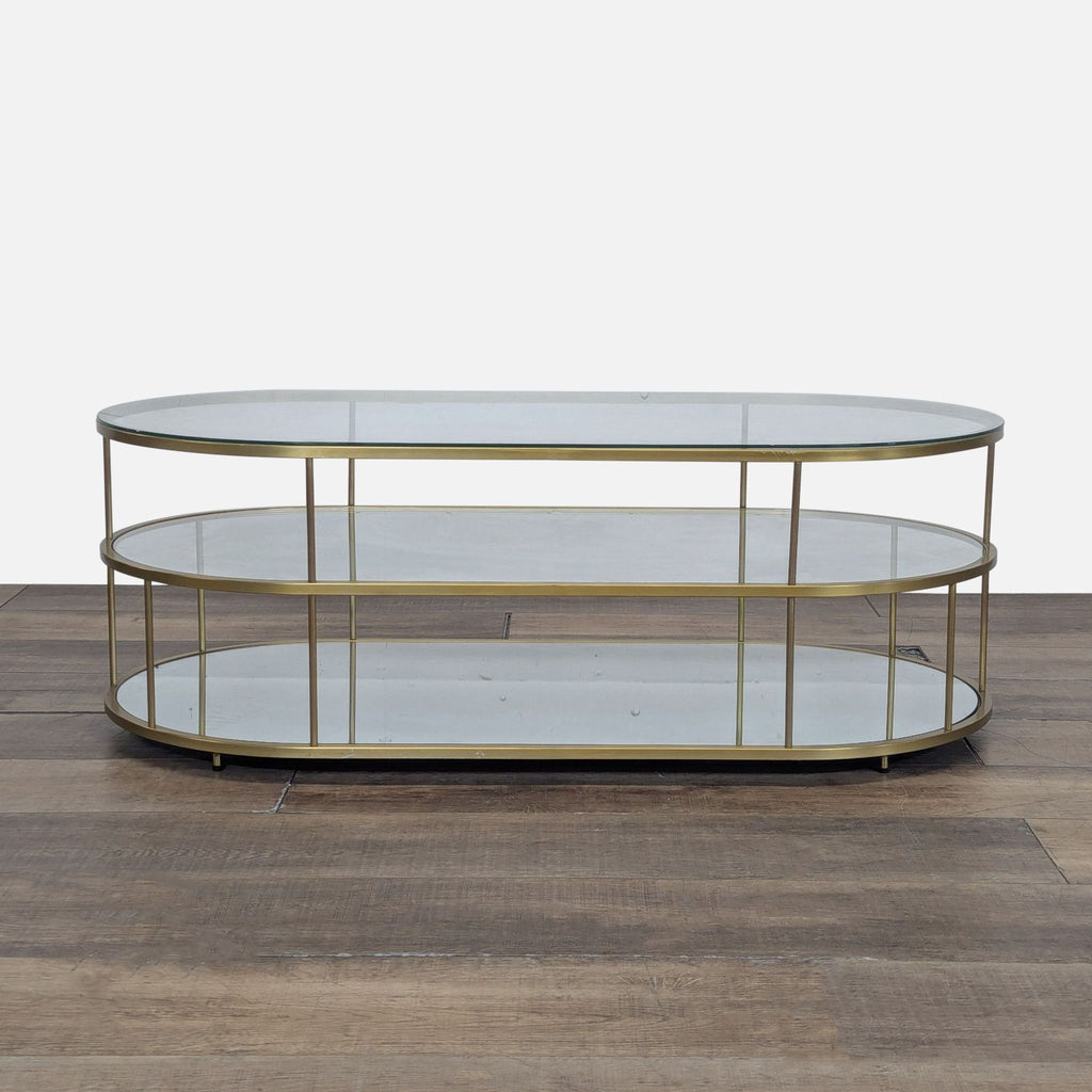 1. Oval-shaped West Elm coffee table with glass shelves and a gold metal frame, shown on a wood floor.  