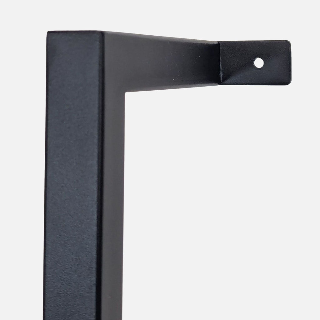 3. Close-up of the black powder coated metal frame from a CB2 bookshelf, highlighting wall-mounting detail.