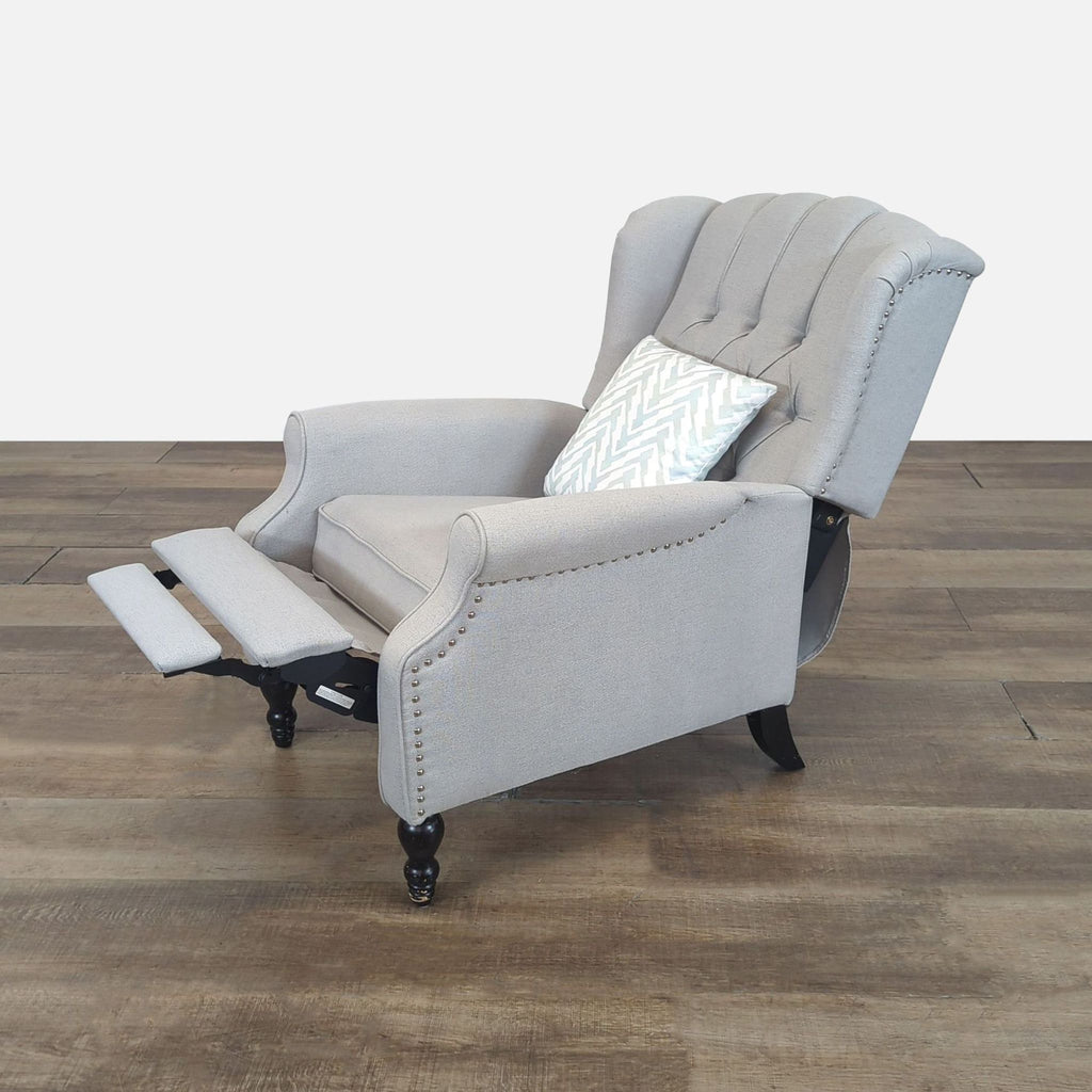2. Side view of reclining gray lounge chair showing push-back function, nailhead trim, and patterned pillow.