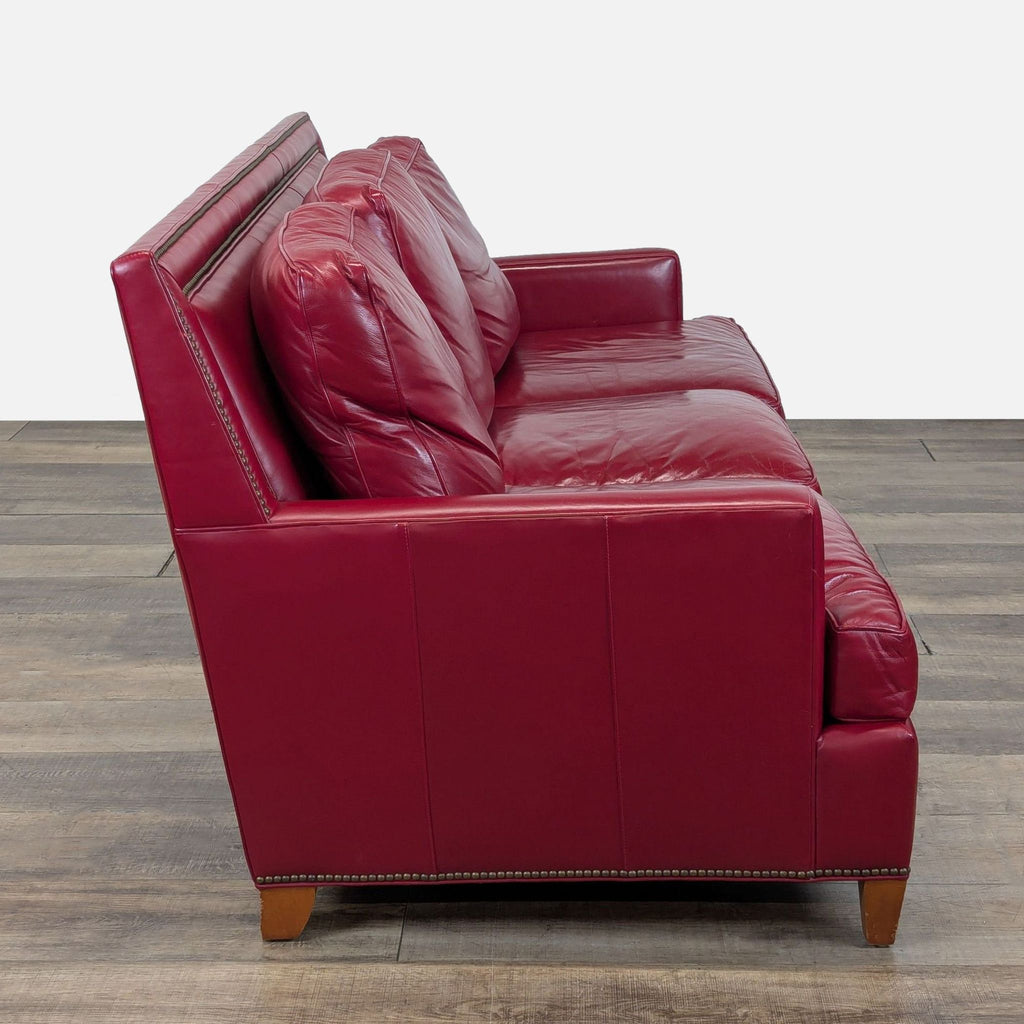 2. Side view of a red leather Hancock & Moore 3-seat sofa, showing track arms and nailhead detailing on the base.