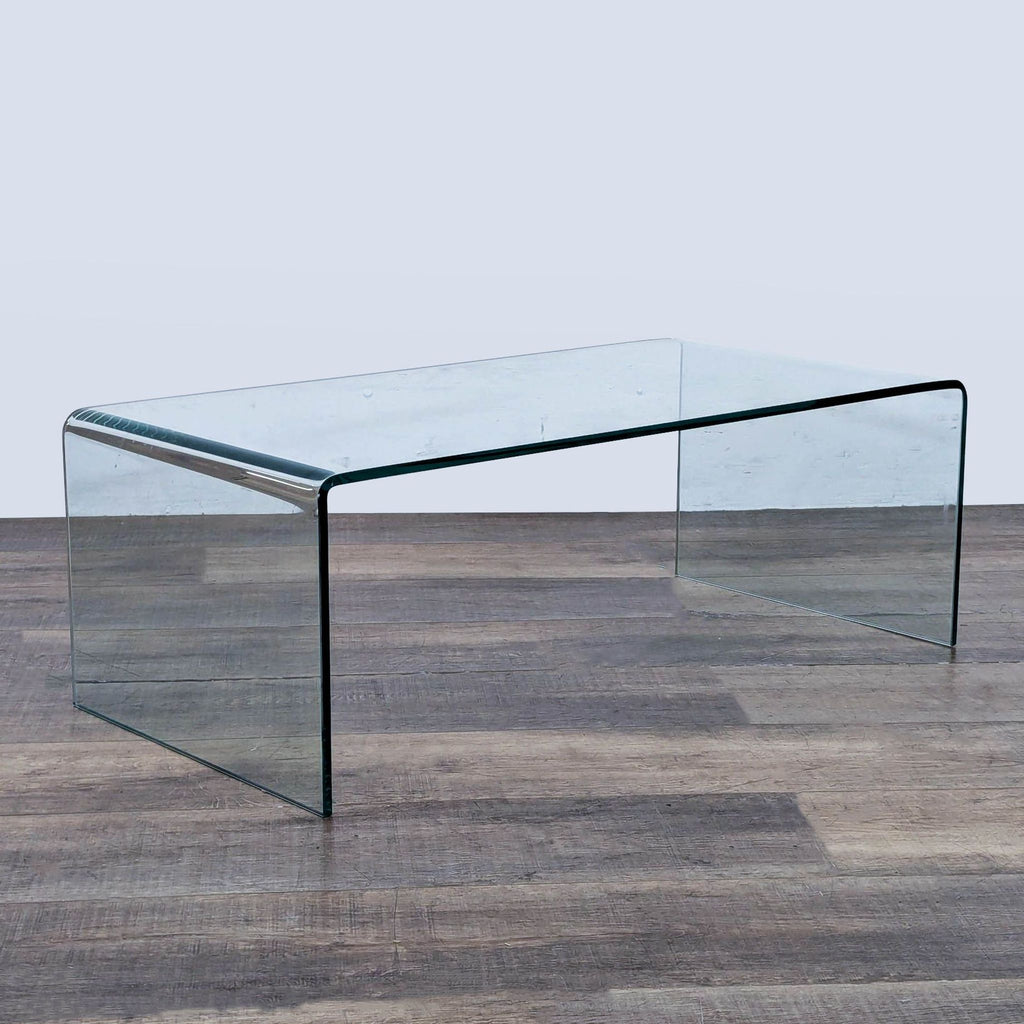 Contemporary transparent Ivy Bronx coffee table featuring a single-piece bent glass construction for a modern look.