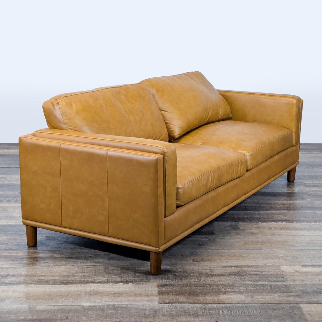 3. Angled view of Wade Logan 3-seat sofa highlighting leather upholstery, track arms, stitching, and wood legs.