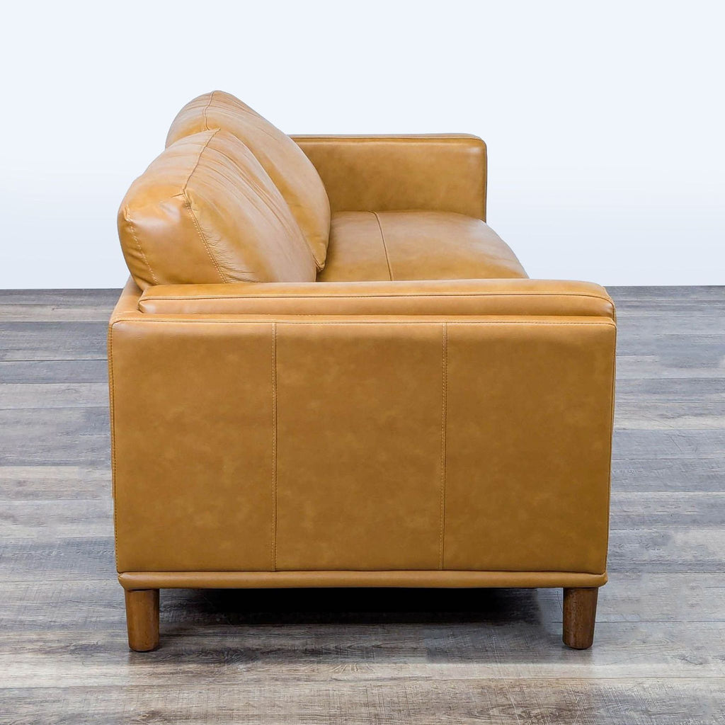 2. Side profile of a Wade Logan 3-seat leather couch showing arm detail, wood legs, and stitched upholstery.