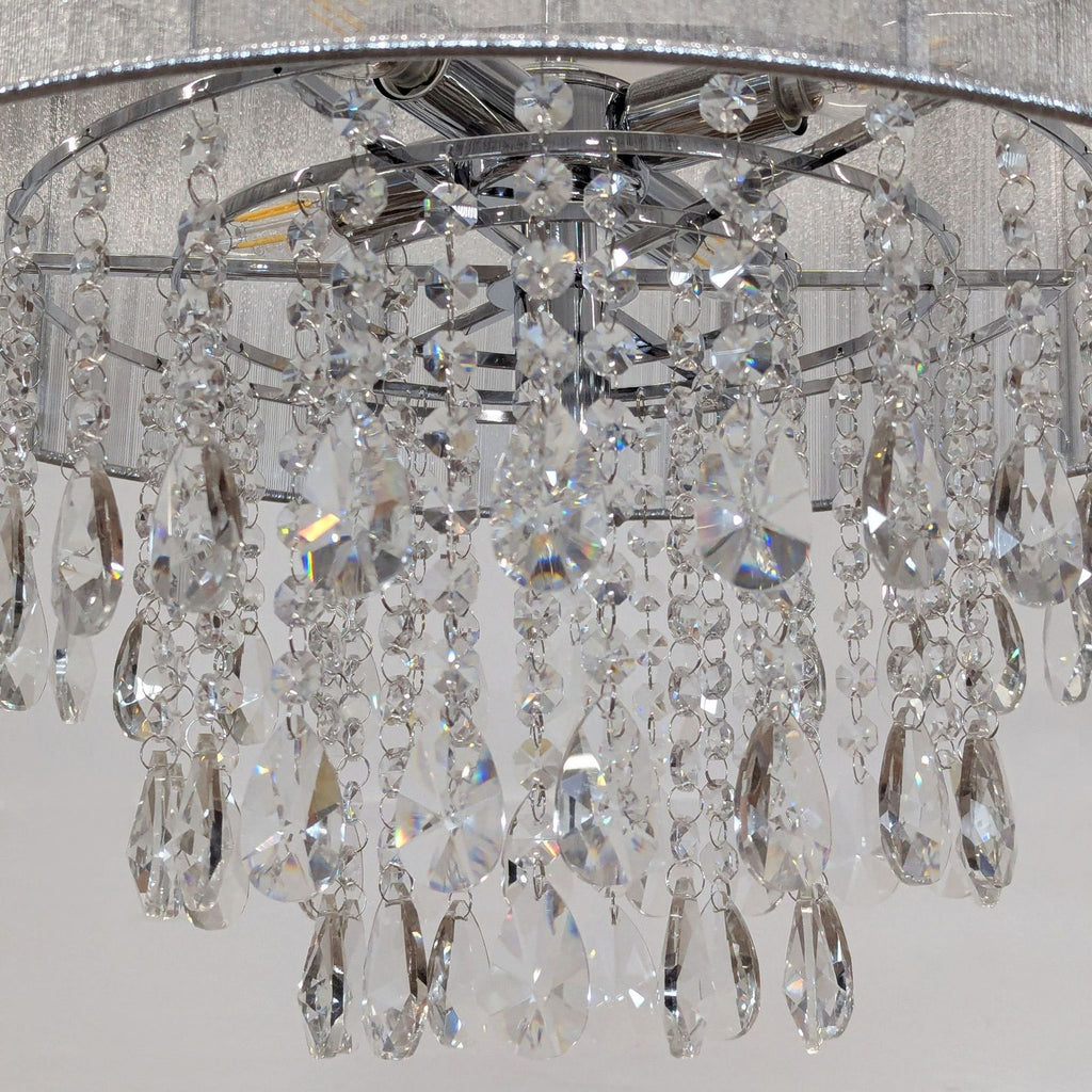 3. Close-up of hanging prisms on a Reperch chrome chandelier with sheer metallic fabric shade.