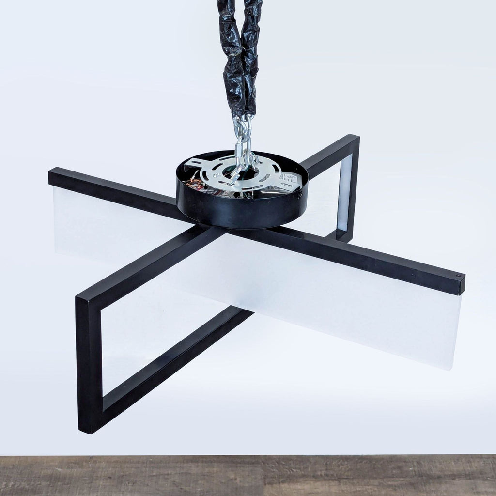 1. Modern black cross-shaped pendant light by Reperch, featuring frosted white panels and suspended by a chain.  