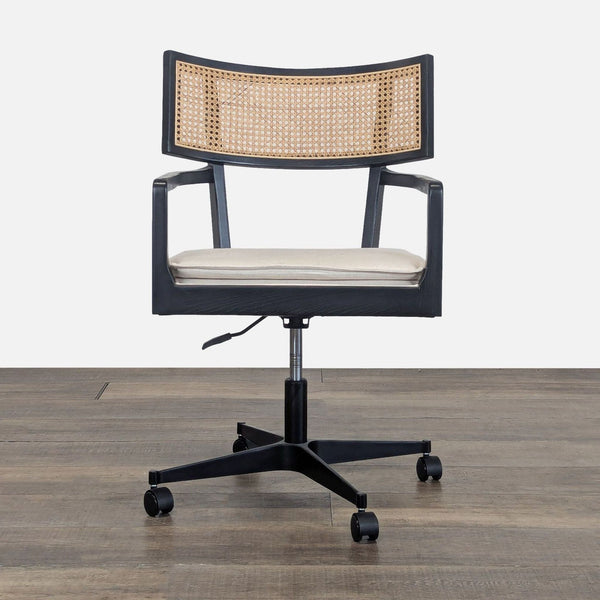 1. Front view of the Crate & Barrel Libby desk chair featuring a cane backrest, cushioned seat, and caster wheels.
