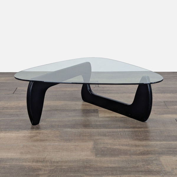 1. Reperch Noguchi coffee table with glass top and black interlocking wood base on wood floor.