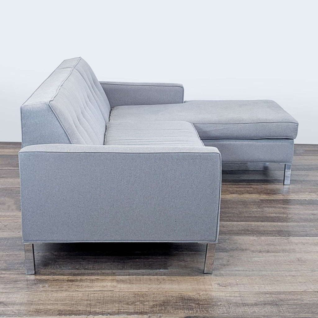2. Side view of a light gray L-shaped sectional by Reperch, showing button-tufted detail and metal legs.