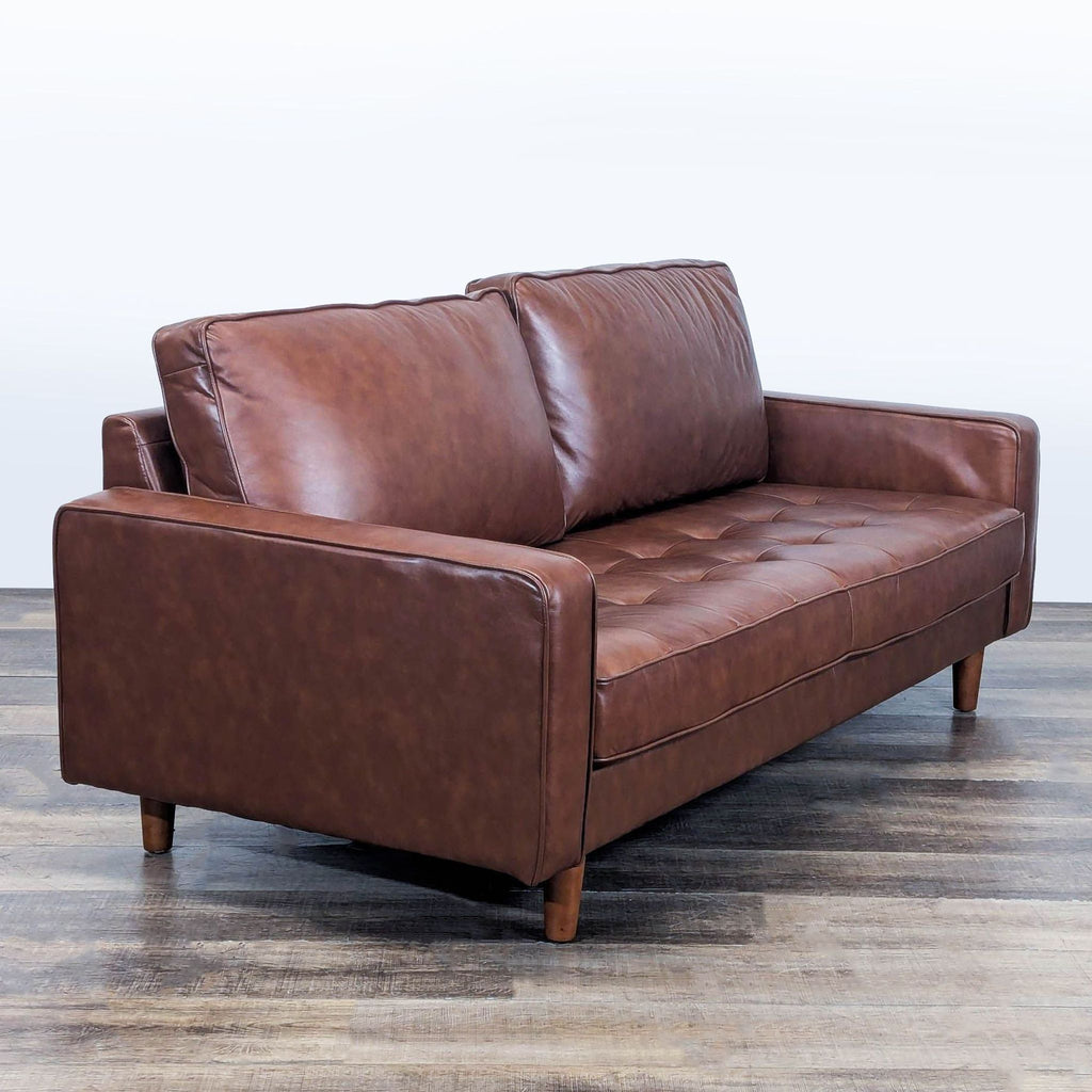 Angled view of Abbyson 3-seat sofa featuring brown tufted leather upholstery and sturdy wooden legs.