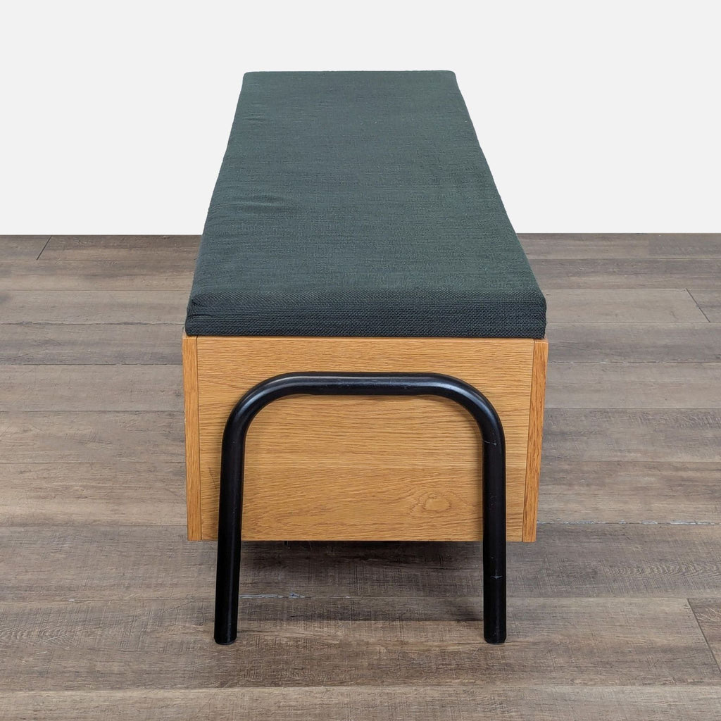 3. Side view of a CB2 bench featuring a black cushion, light wood panels, and rounded black metal legs.