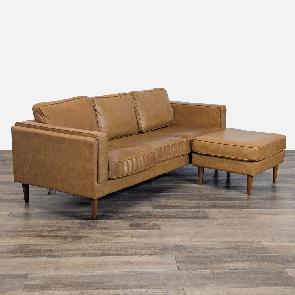 2. Side angle of Albany Park 3-seat vegan leather sofa, tapered walnut legs and matching ottoman.
