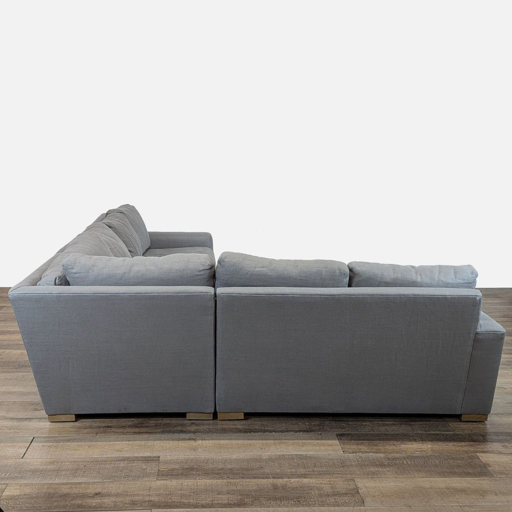 3. Side view of a gray Restoration Hardware modular sectional with plush cushions and wood block feet on a wood floor.