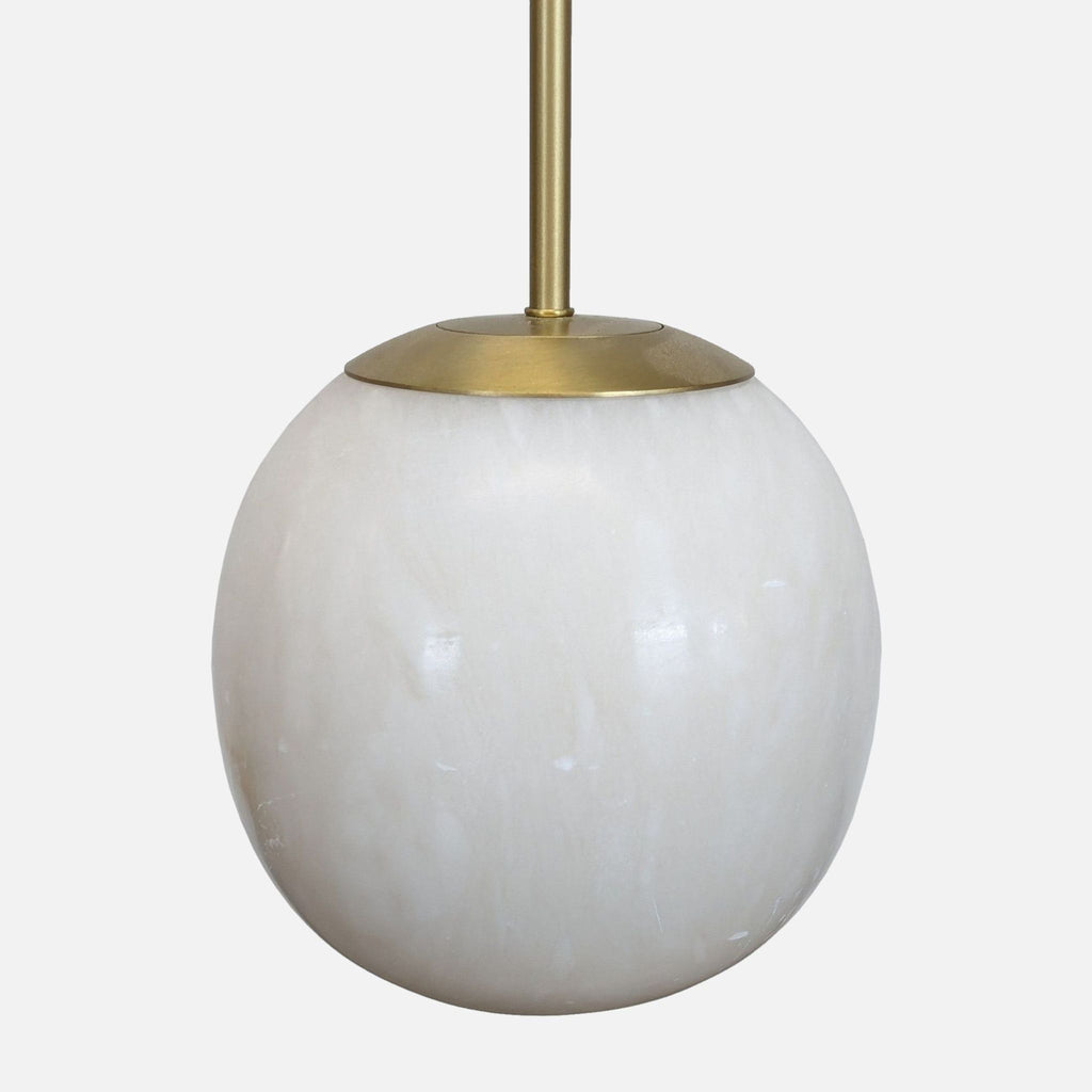 Close-up of the CB2 Savina Pendant’s alabaster globe and brass fixture detail for lighting.