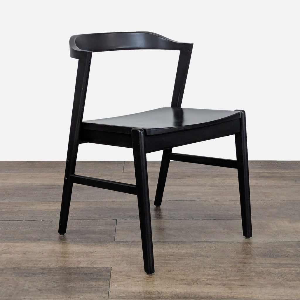 Single black Reperch dining chair shown at an angle, highlighting its minimalist, modern design.  