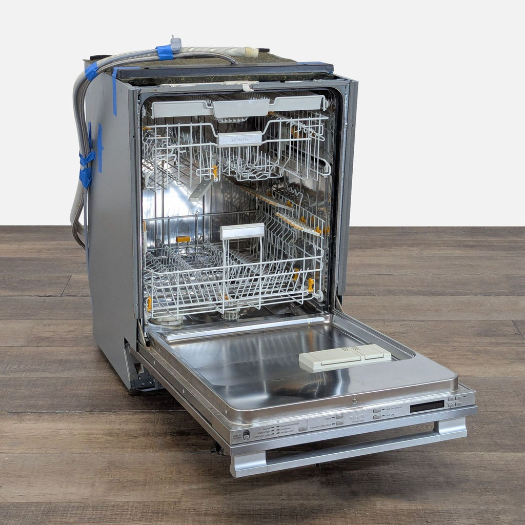 2. Open Miele dishwasher showing spacious interior racks, cutlery tray, and stainless steel inner door.