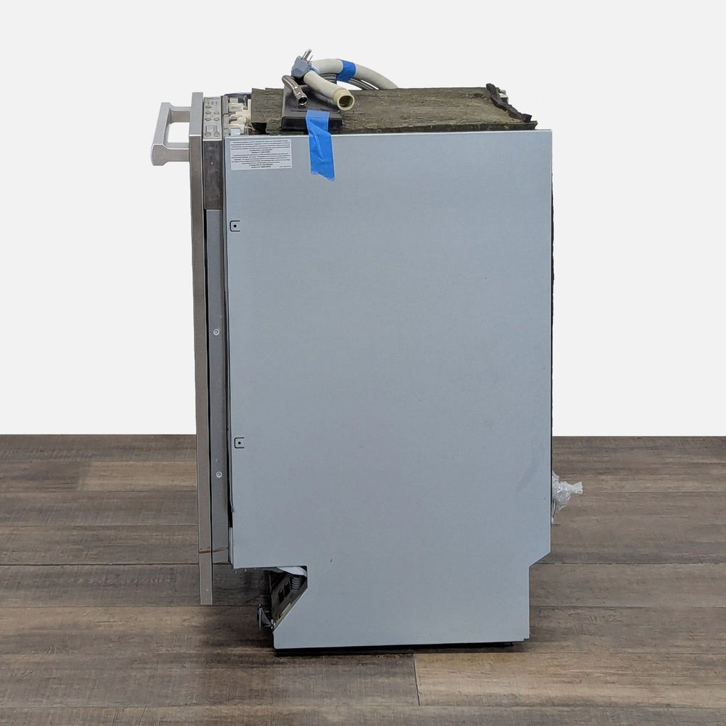 3. Side view of the Miele G6875SCVI dishwasher displaying its unfinished panel-ready exterior and attached hoses.