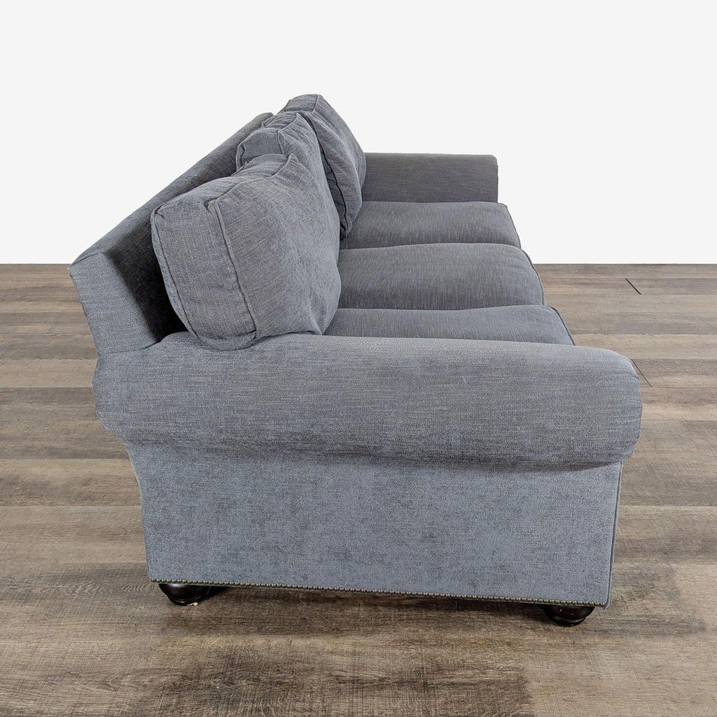 2. Side view of a Pottery Barn 3-seat sofa in fabric with rolled arms and nailhead trim detail.