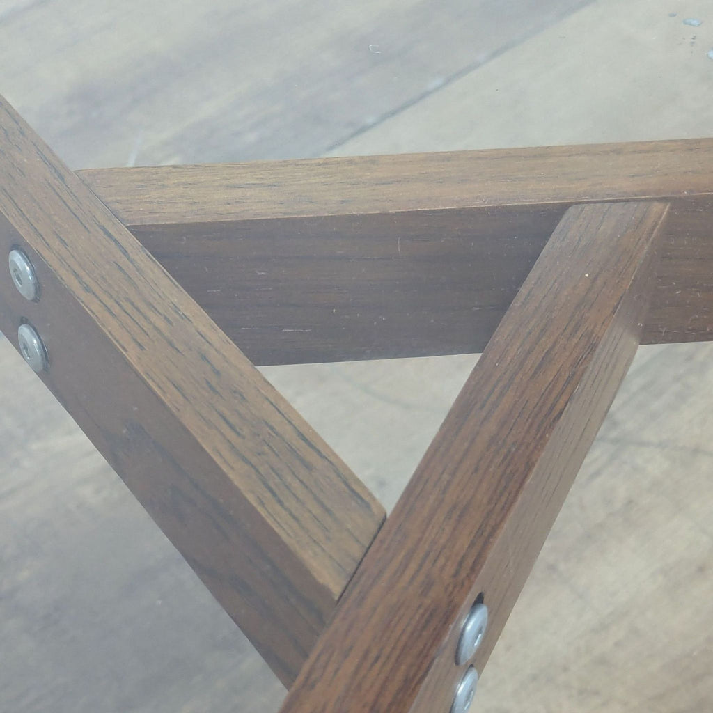 3. Close-up view of the wooden leg structure and supports of the Article coffee table under glass.