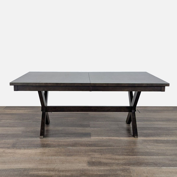 1. Living Spaces dining table with a cross-legged base and 18” extension leaf, shown on wood flooring.