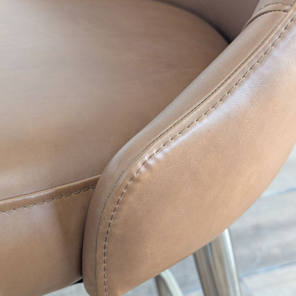 3. Close-up detail of the West Elm stool’s brown leather upholstery and stitching at the arm and seat edge.