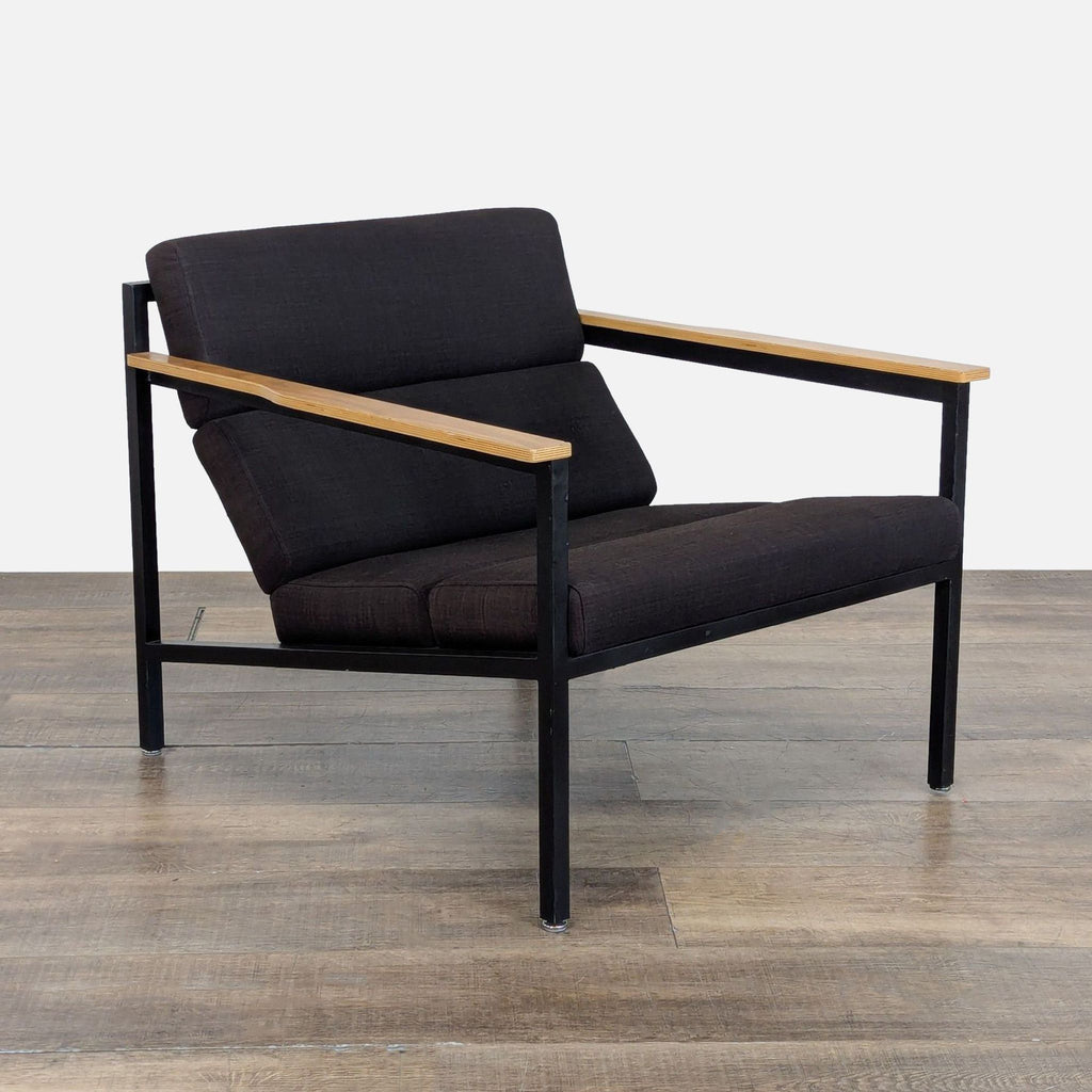 Angled view of a Gus* lounge chair showing powder-coated steel frame, wood paddle arms, and faceted upholstery panels.