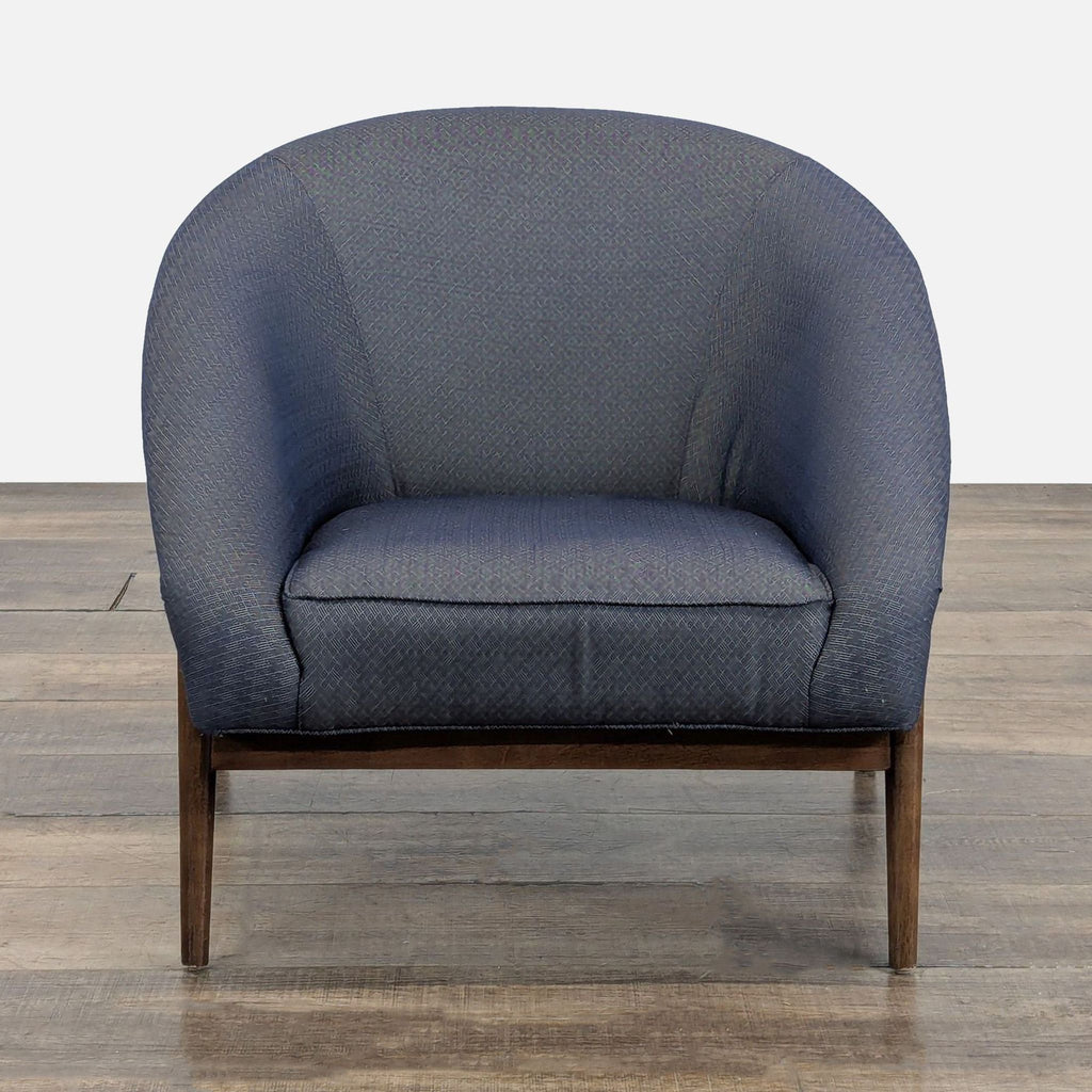 Front view of a dark blue Reperch lounge armchair with textured fabric and dark wooden legs.  