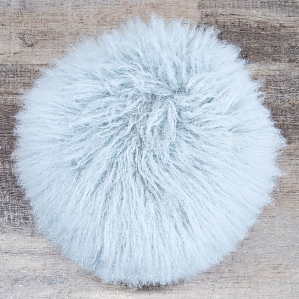 3. Top view of a round Interlude Home bench, covered in plush ivory sheepskin and stainless steel base.