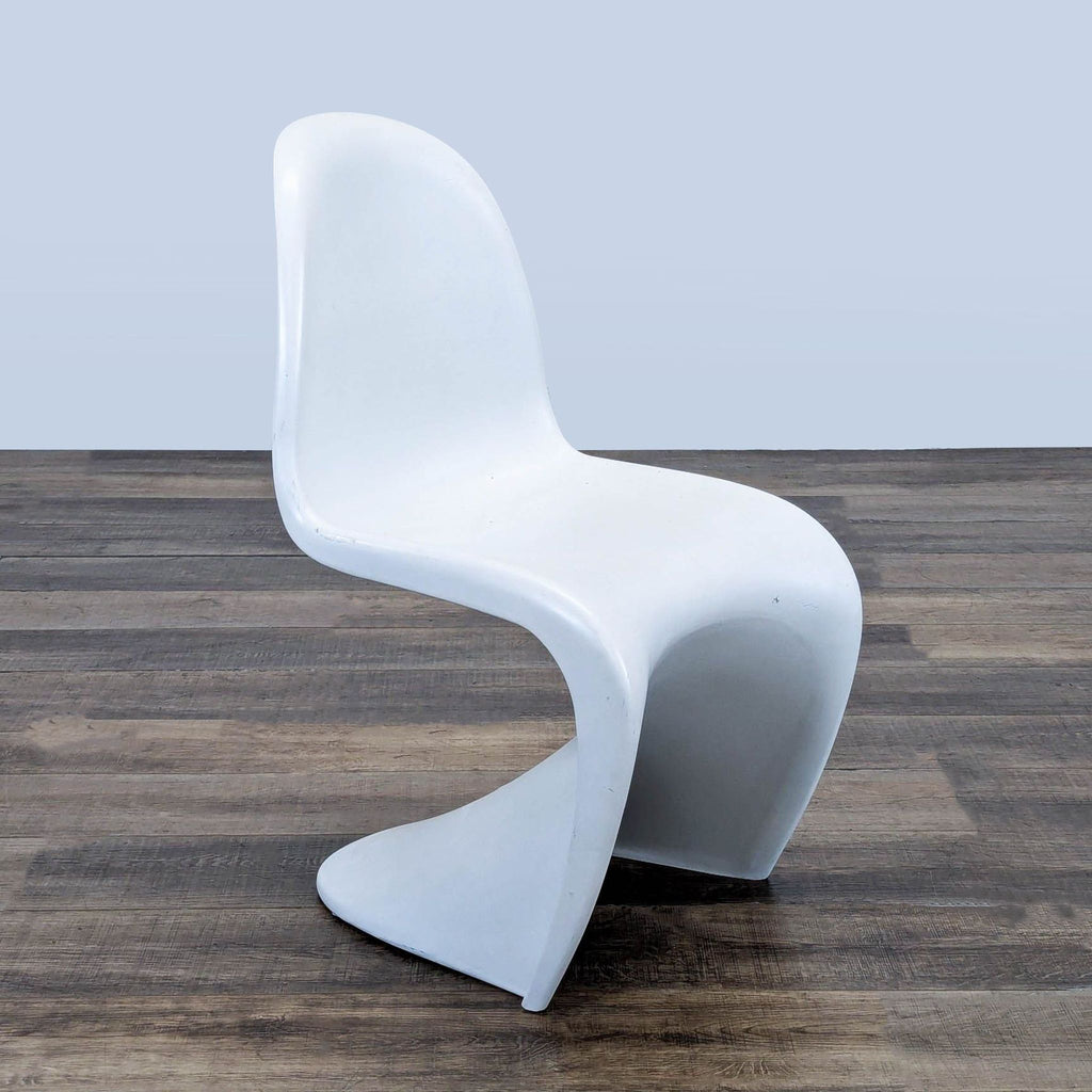 White plastic Panton Chair by Reperch, featuring a sleek, single-mould design, shown on wood flooring.  