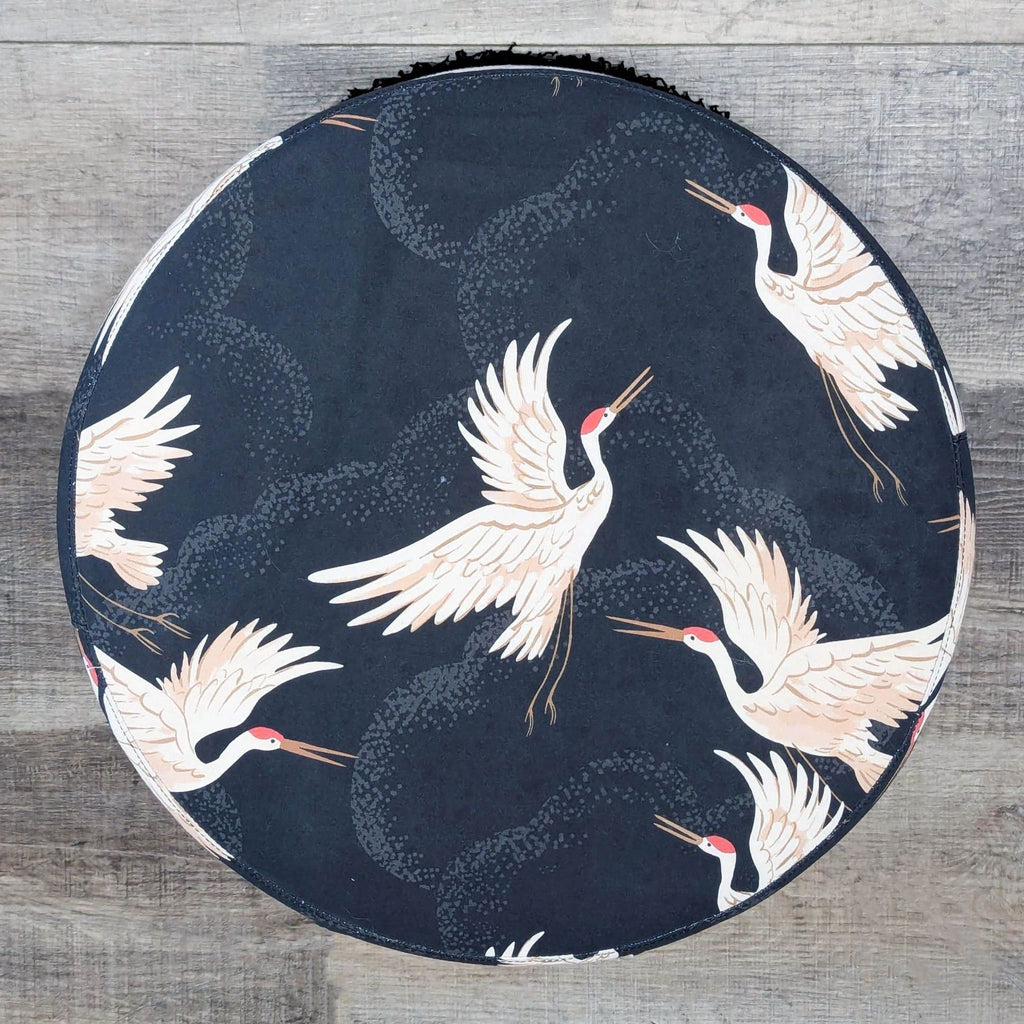 3. Top view of a circular Skyline Furniture ottoman upholstered in navy fabric with white crane designs.