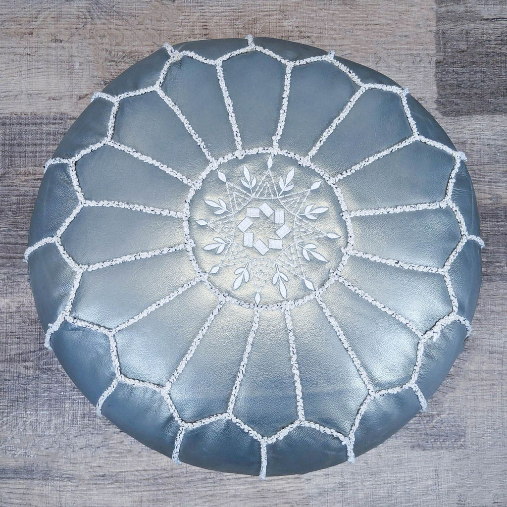 2. Top view of a silver Reperch ottoman showing intricate white stitching and floral pattern.