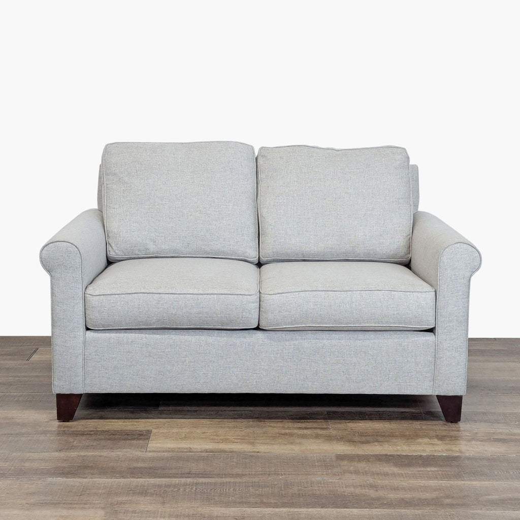 1. Front view of a Pottery Barn loveseat with wood block feet, rolled arms, and loose cushions.