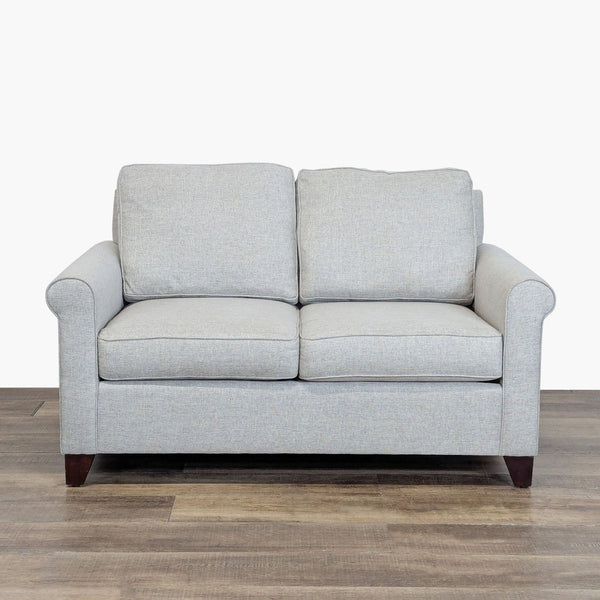 1. Front view of a Pottery Barn loveseat with wood block feet, rolled arms, and loose cushions.
