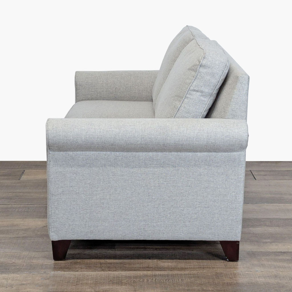 3. Opposite side view of a Pottery Barn loveseat featuring wood block legs and plush loose cushions.