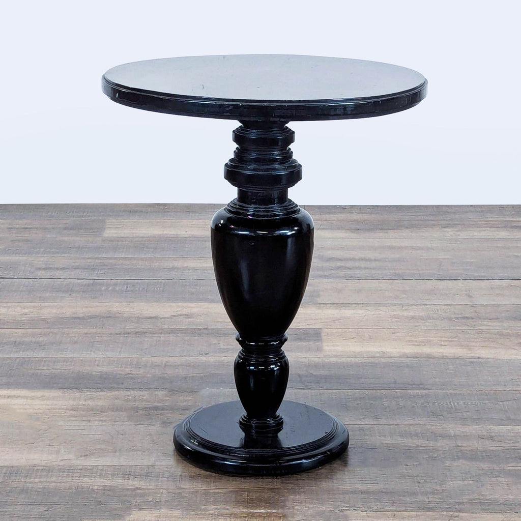 1. Reperch black side table with round top and turned pedestal base, placed on wood flooring.