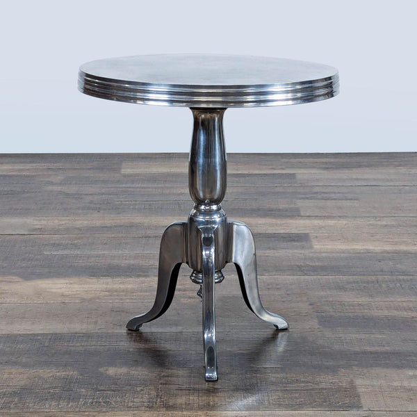 1. Reperch aluminum side table with round top and three curved legs, placed on a wooden floor.  