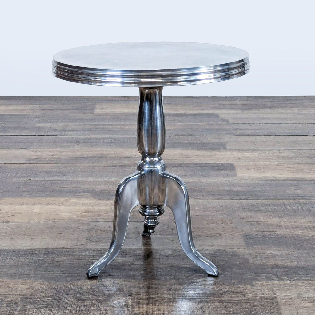 2. Shiny aluminum console table by Reperch, featuring a circular top and a sturdy tripod pedestal base.  