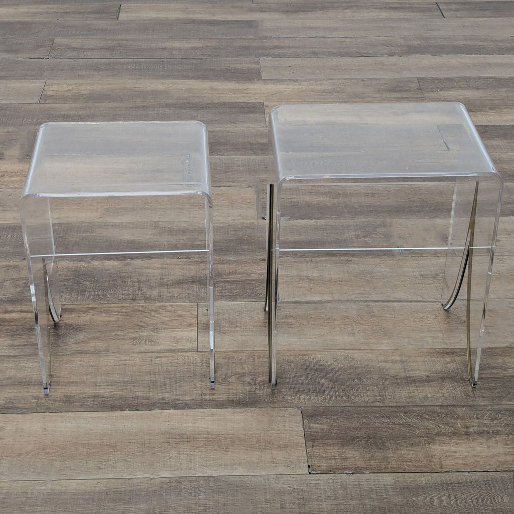 3. Two transparent acrylic Gabby Magnolia end tables with antique brass detail, shown on a rustic floor.
