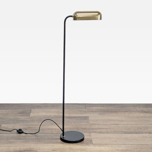 1. Full view of a Reperch floor lamp with a blackened bronze body and a brass shade, shown on wood flooring.