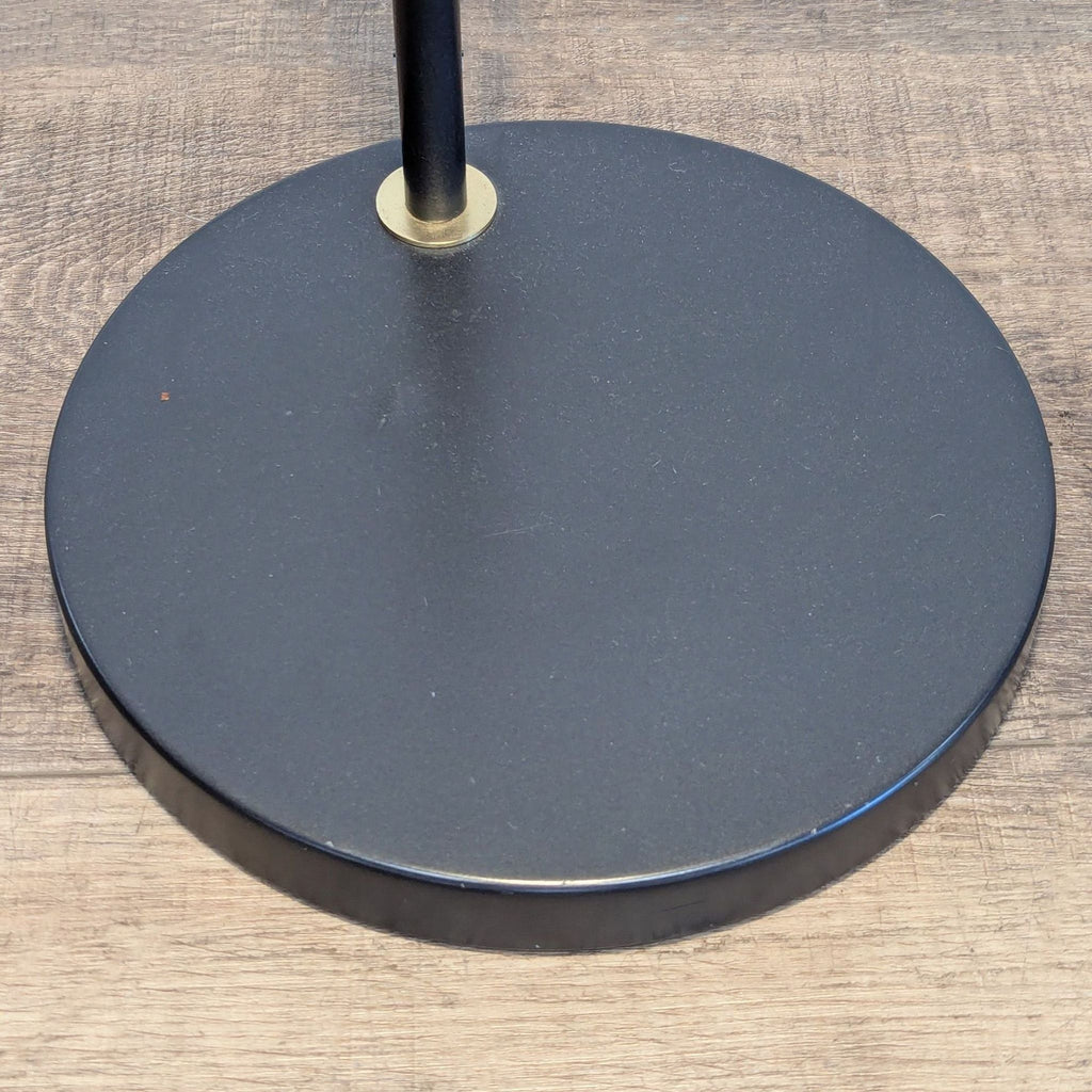 3. Detailed shot of the Reperch lamp's round blackened bronze base on a wood floor, showing sturdy construction.
